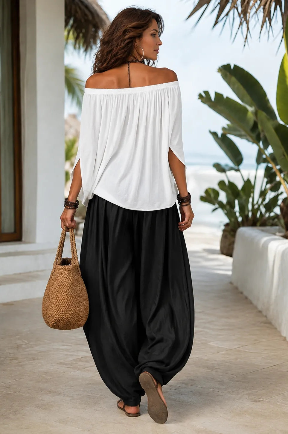 Side profile of a model wearing the flowing black trousers, showcasing their relaxed drape.