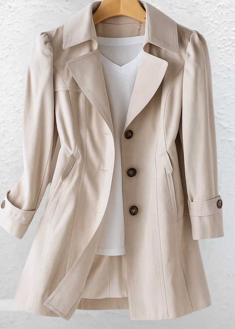 Close-up detail of the beige fabric and button closure of the Adeline trench coat, highlighting material quality.