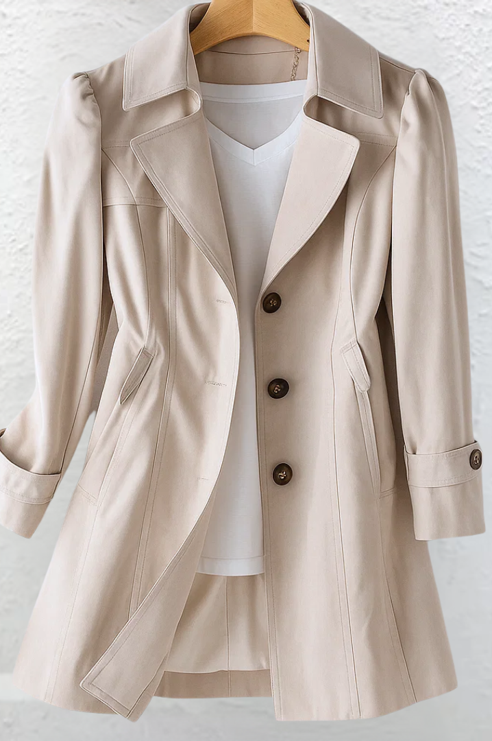 Close-up detail of the beige fabric and button closure of the Adeline trench coat, highlighting material quality.