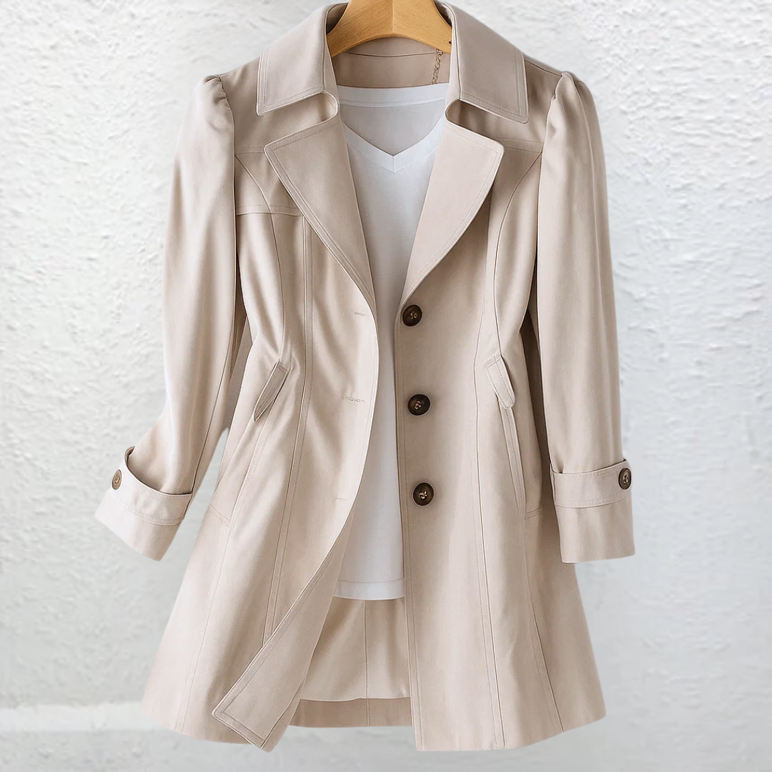 Close-up detail of the beige fabric and button closure of the Adeline trench coat, highlighting material quality.