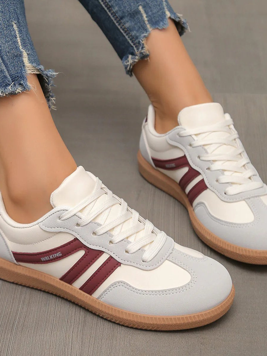 Woman's feet wearing black Elara orthopaedic cushioned trainers, captured during a relaxed walk in a park setting.