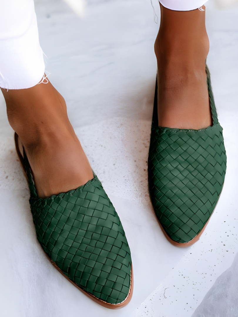 Side profile of a green handcrafted moccasin on a light background, highlighting the flexible sole and artisanal stitching.