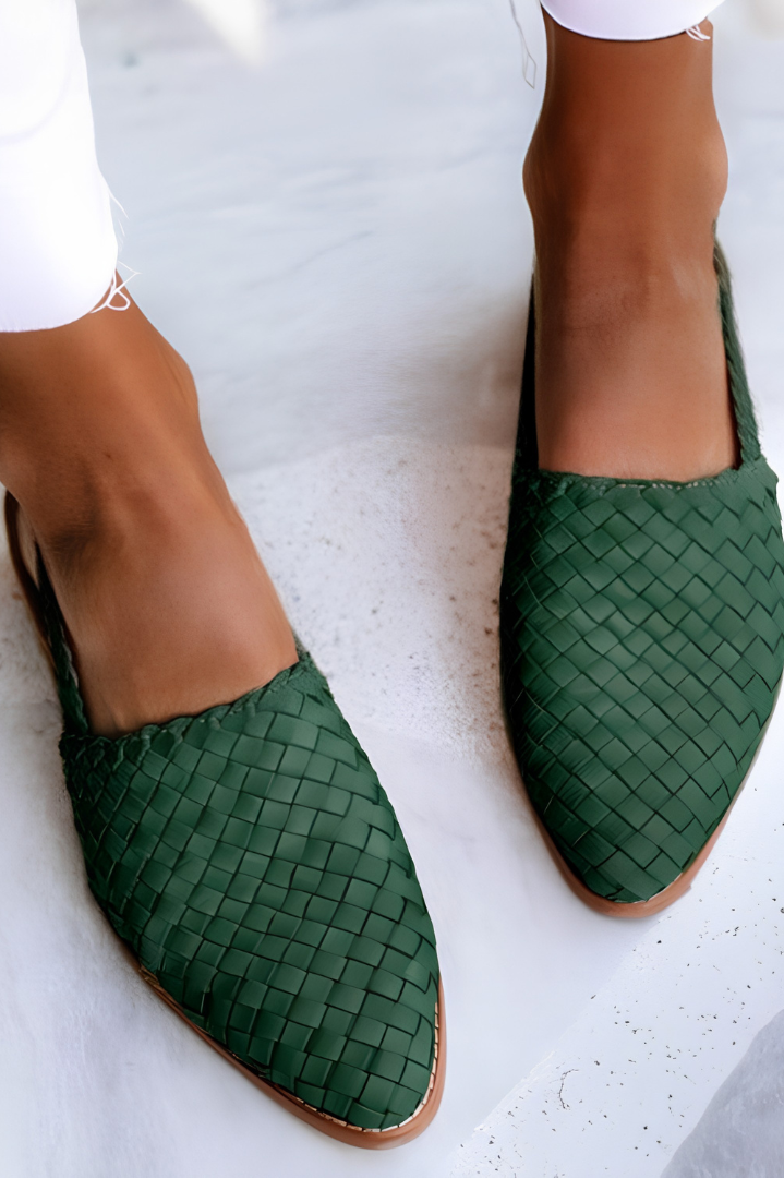 Side profile of a green handcrafted moccasin on a light background, highlighting the flexible sole and artisanal stitching.