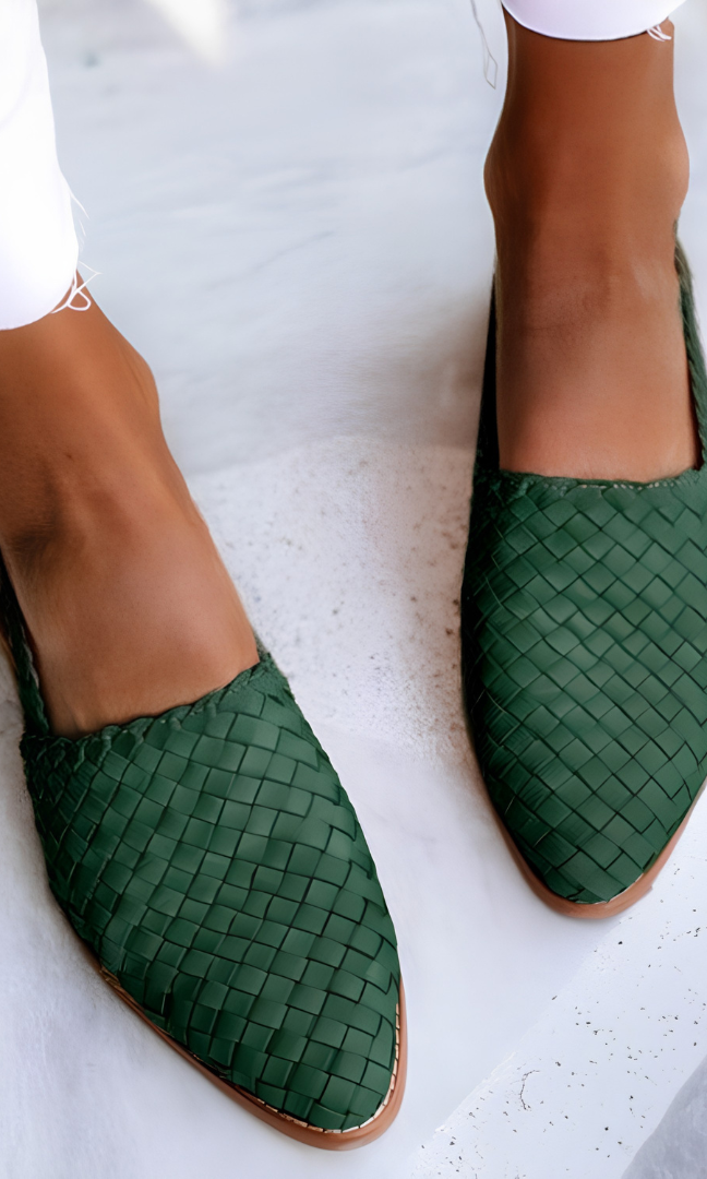 Side profile of a green handcrafted moccasin on a light background, highlighting the flexible sole and artisanal stitching.