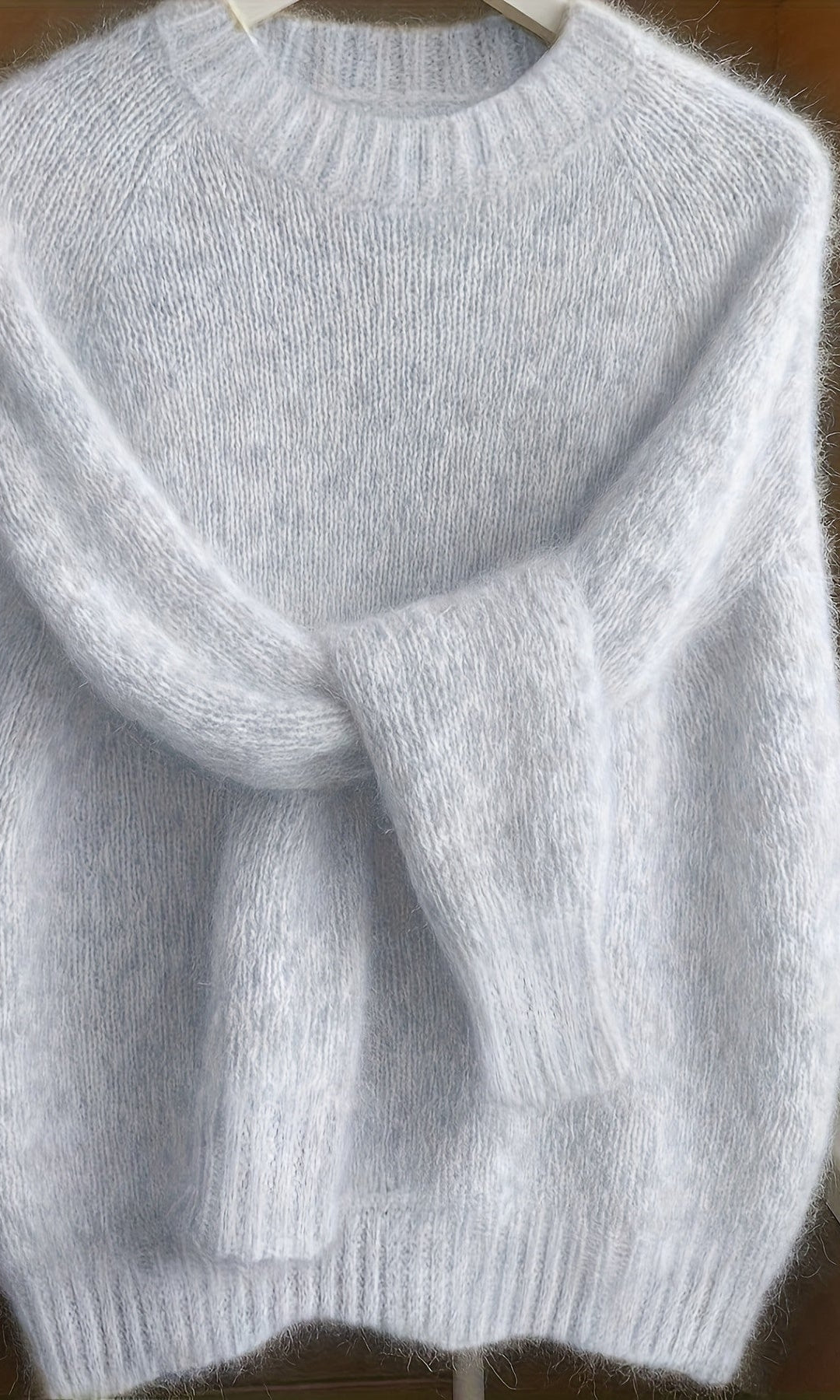 Side profile of a woman in the light grey Elara cashmere-blend sweater, highlighting the elegant silhouette and sleeve length.