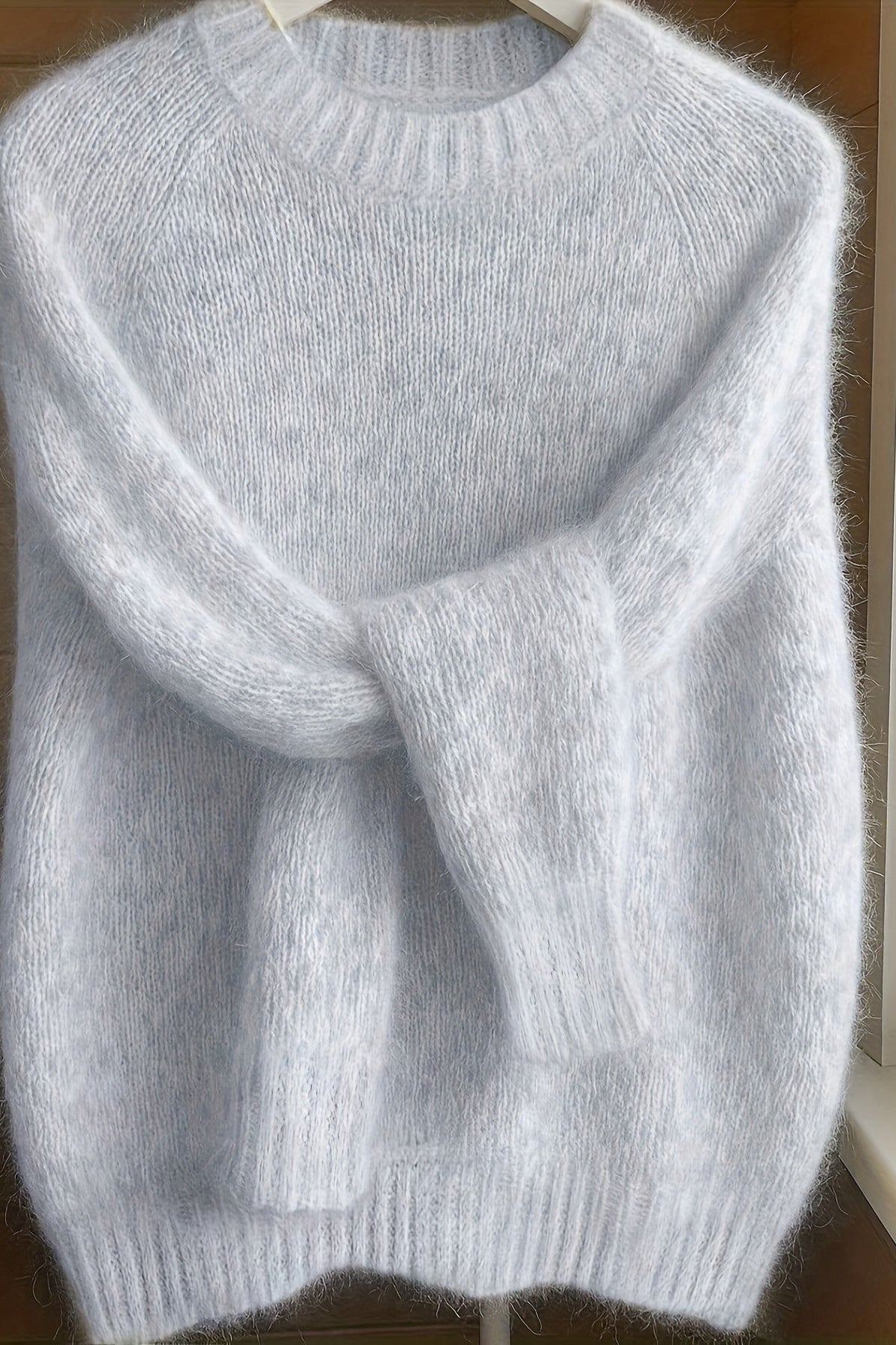 Side profile of a woman in the light grey Elara cashmere-blend sweater, highlighting the elegant silhouette and sleeve length.