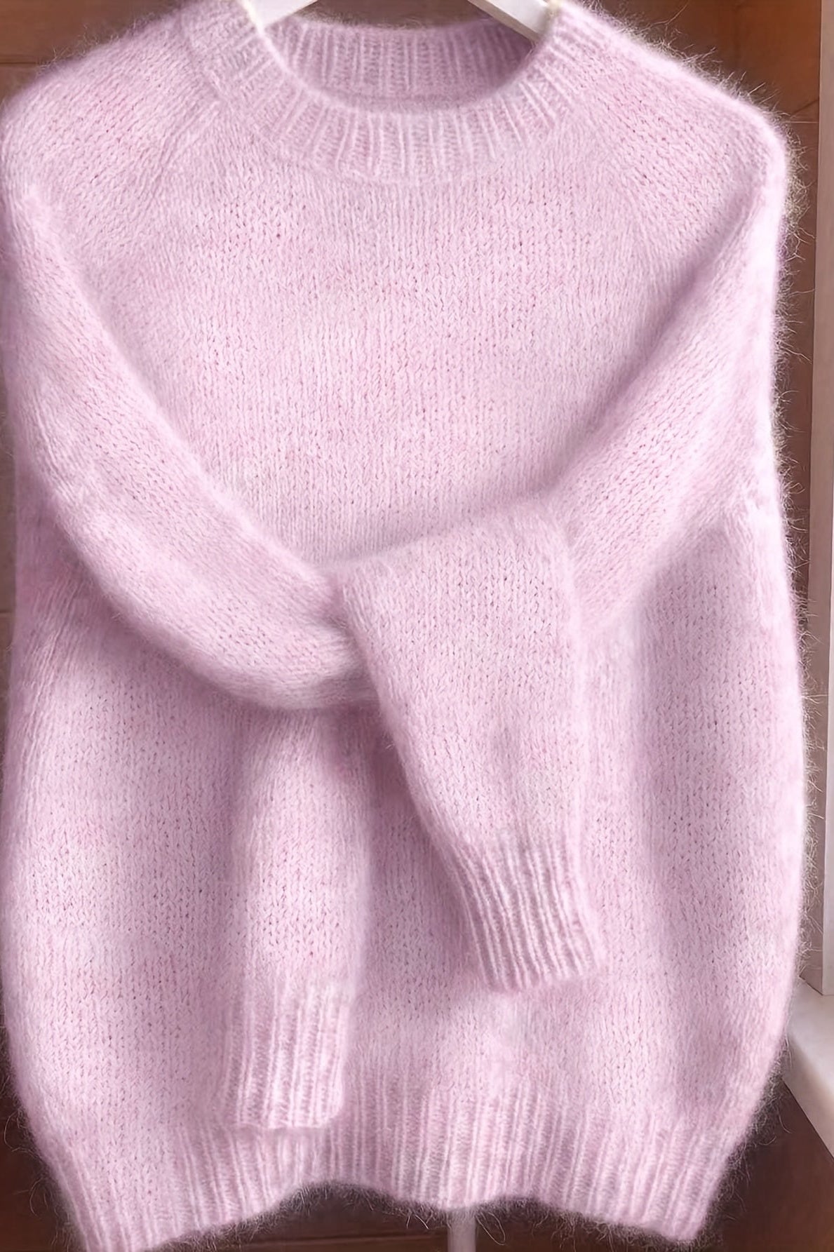 A stack of folded Elara cashmere-blend sweaters in various colors, emphasizing the quality and rich palette.