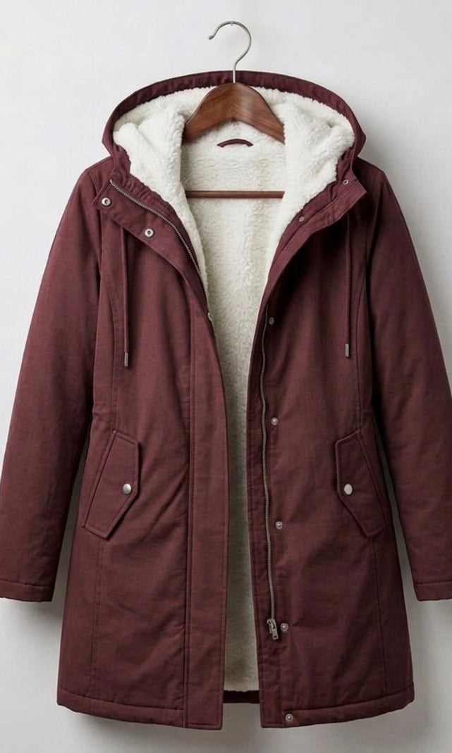 A woman wearing the Elara waterproof parka in a natural outdoor setting, protected from light rain.