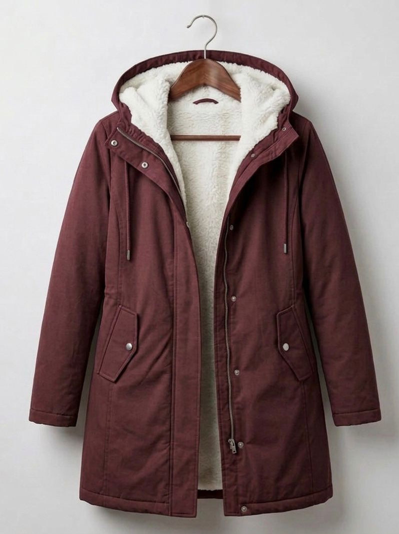 A woman wearing the Elara waterproof parka in a natural outdoor setting, protected from light rain.