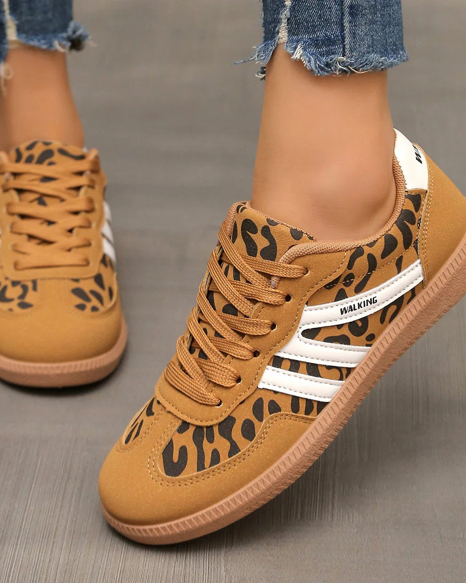 Lifestyle shot of a woman wearing off-white Elara orthopaedic cushioned trainers while walking outdoors, showing comfort in motion.