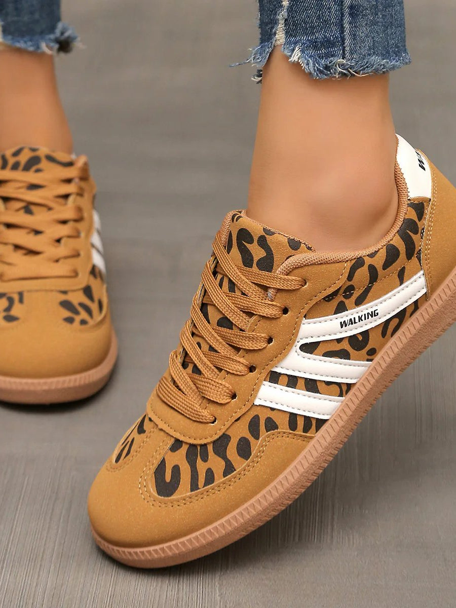 Lifestyle shot of a woman wearing off-white Elara orthopaedic cushioned trainers while walking outdoors, showing comfort in motion.