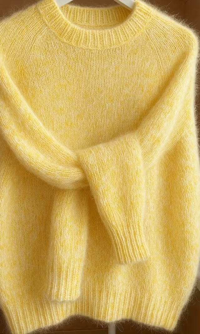Detail shot of the crew neck and shoulder seam of the orange Elara cashmere-blend sweater, focusing on craftsmanship.