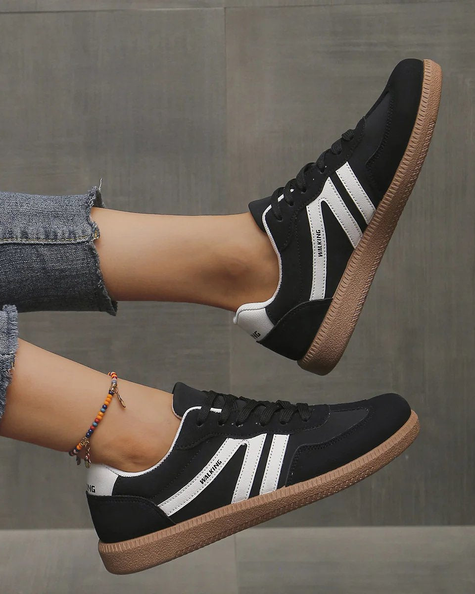 Angled shot of the black Elara orthopaedic cushioned trainer, showcasing its contrast sole and secure lacing system.