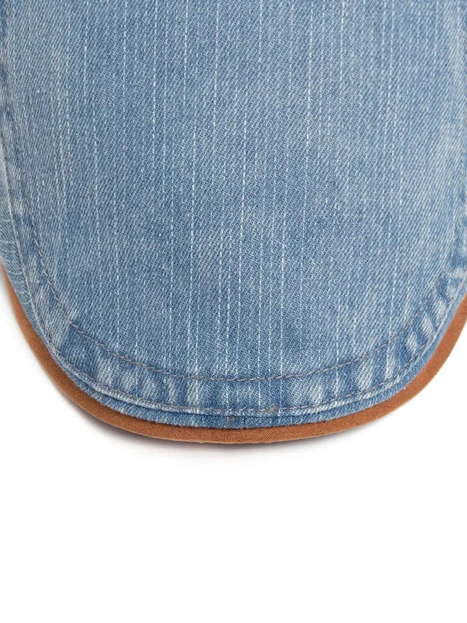 A close-up of the black denim flat cap texture, illustrating the durable and soft feel of the material.