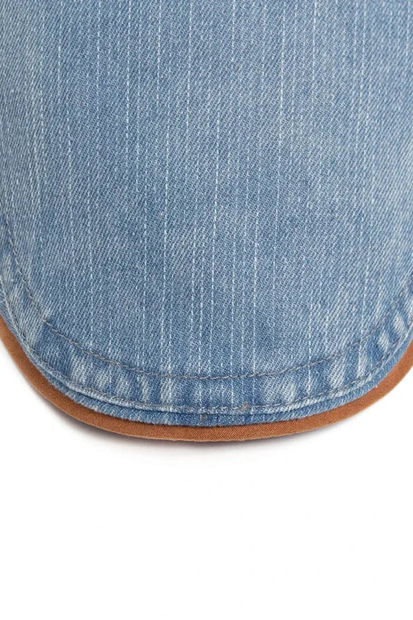 A close-up of the black denim flat cap texture, illustrating the durable and soft feel of the material.