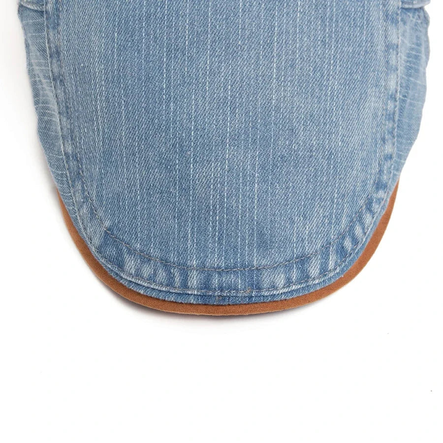 A close-up of the black denim flat cap texture, illustrating the durable and soft feel of the material.