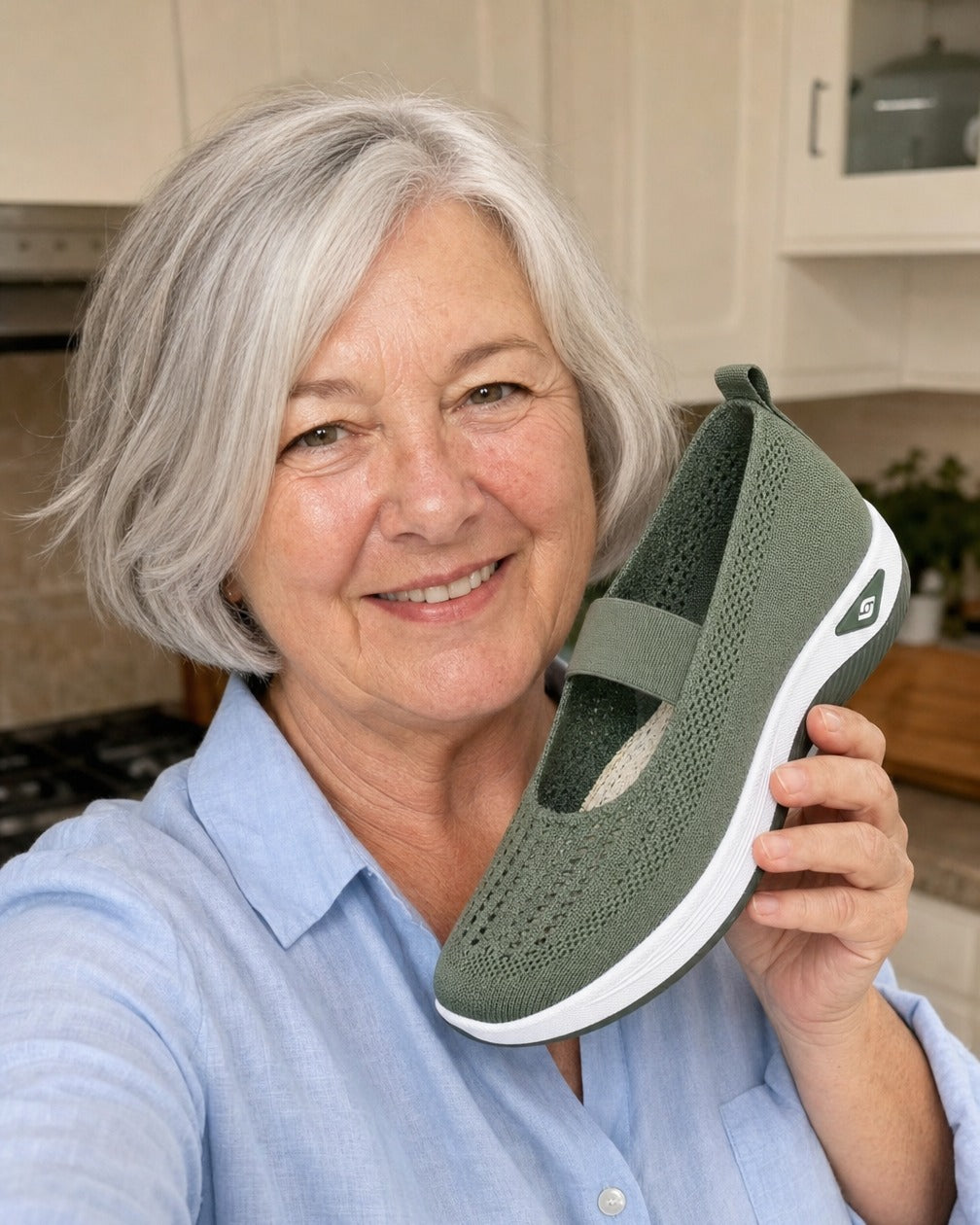 Woman in her 60s smiling and holding the green Carry knit slip-on shoe
