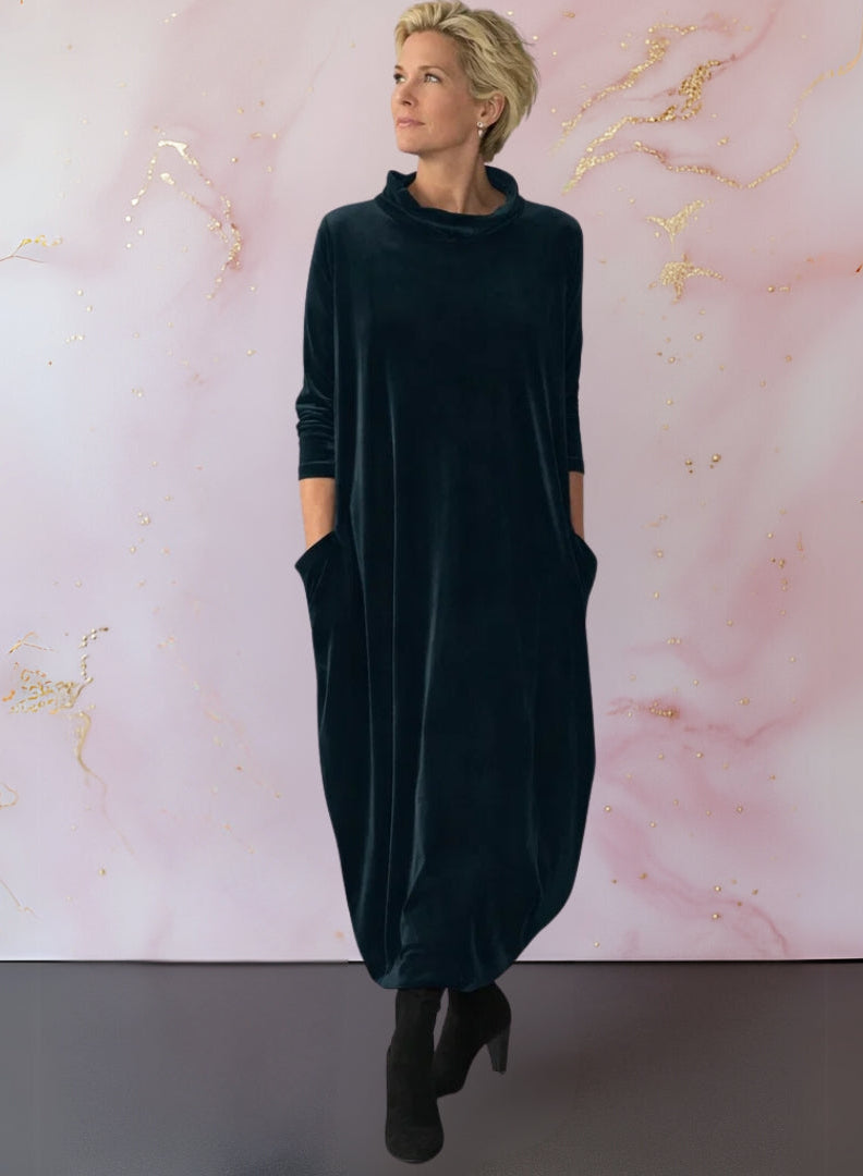 Front view of a woman wearing the Leona velvet maxi dress in dark green, showcasing its elegant draped silhouette.
