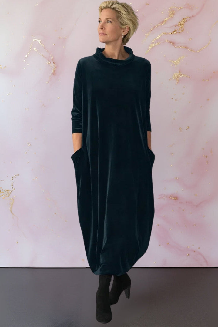 Front view of a woman wearing the Leona velvet maxi dress in dark green, showcasing its elegant draped silhouette.