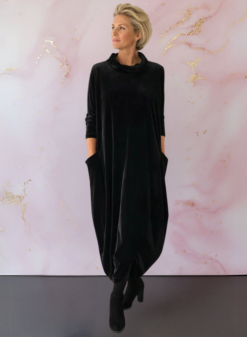 Full-length shot of the Leona velvet maxi dress in blue, styled with ankle boots for a chic daytime look.