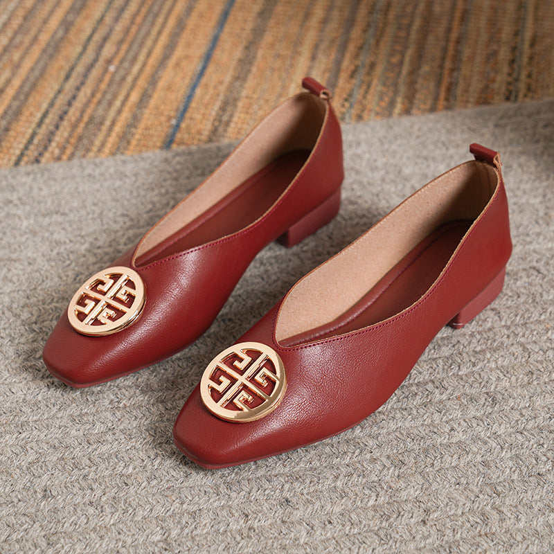 Close-up detail of the striking gold-tone circular accent on a beige square-toe flat, adding a touch of elegance.