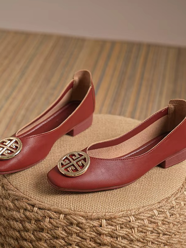 A person wearing stylish red square-toe flats, perfectly complementing tailored pants for a chic ensemble.
