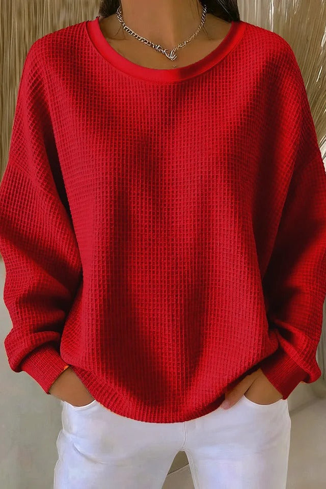 Side profile of a model wearing the Odette knit sweater in red, highlighting the relaxed drape.