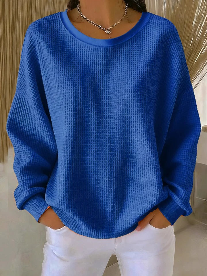 Full-body shot of a woman wearing the Odette knit sweater in blue, paired with casual bottoms.