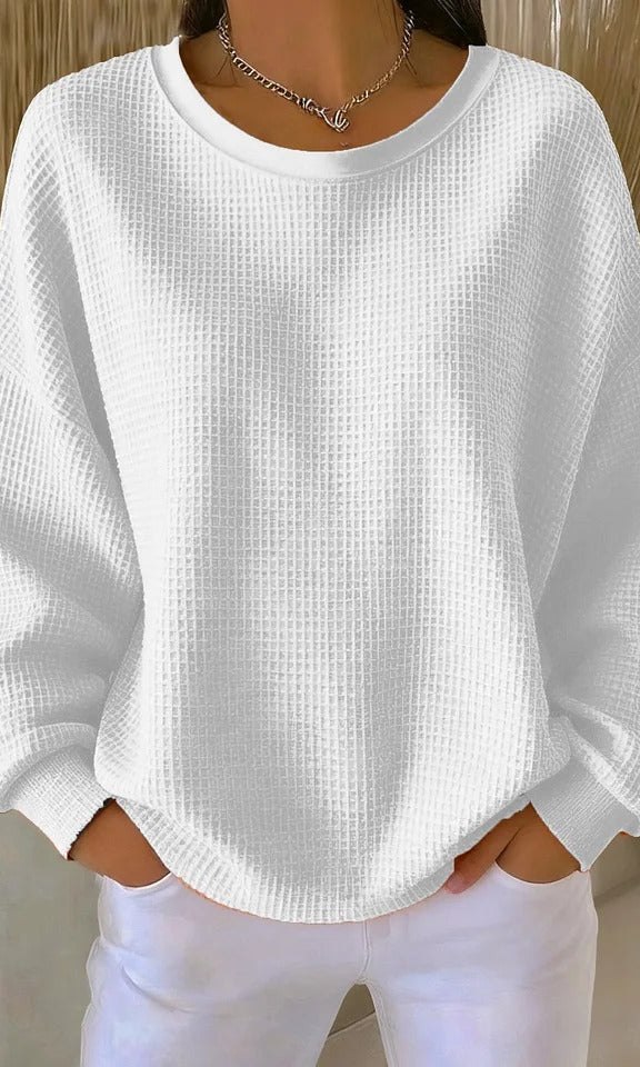 The Odette knit sweater in white, laid flat to display its classic round neckline and simple hem.