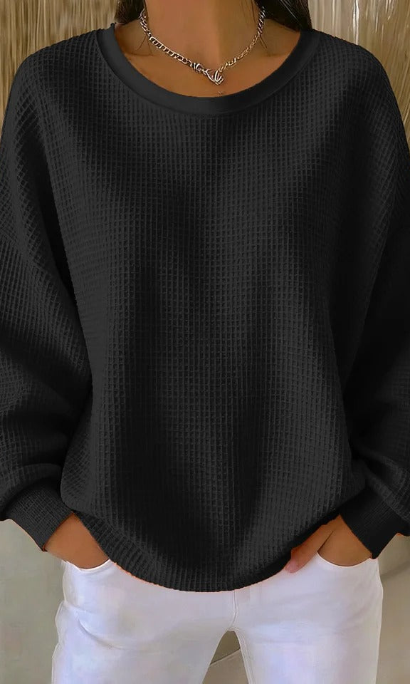 Lifestyle image of the Odette knit sweater in black, worn during a relaxed outdoor setting.