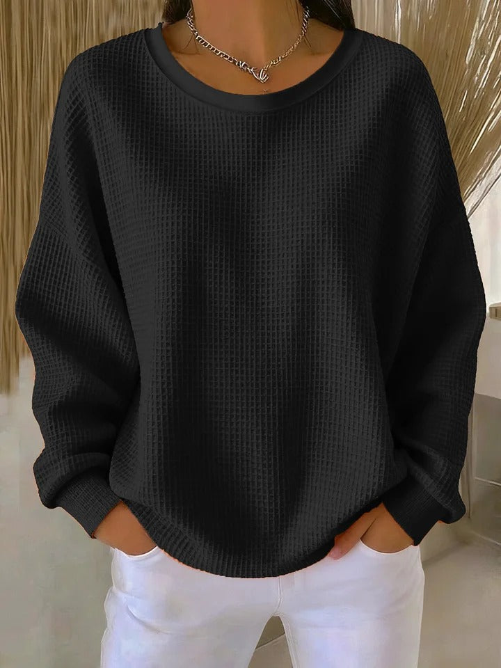 Lifestyle image of the Odette knit sweater in black, worn during a relaxed outdoor setting.
