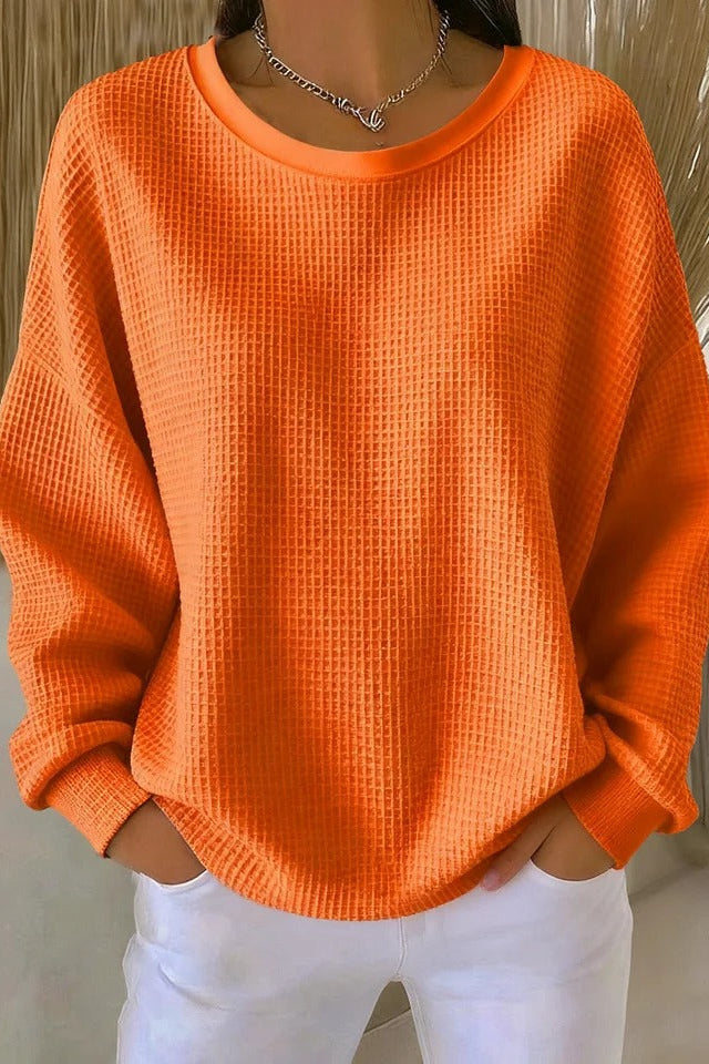 Detail shot of the sleeve cuff on the Odette knit sweater in orange, emphasizing its unpretentious finish.