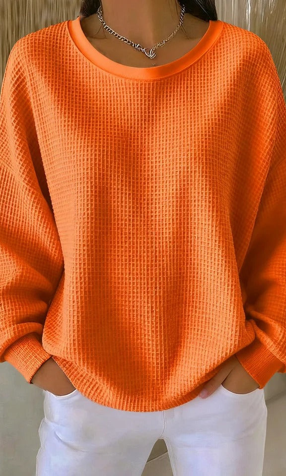 Detail shot of the sleeve cuff on the Odette knit sweater in orange, emphasizing its unpretentious finish.