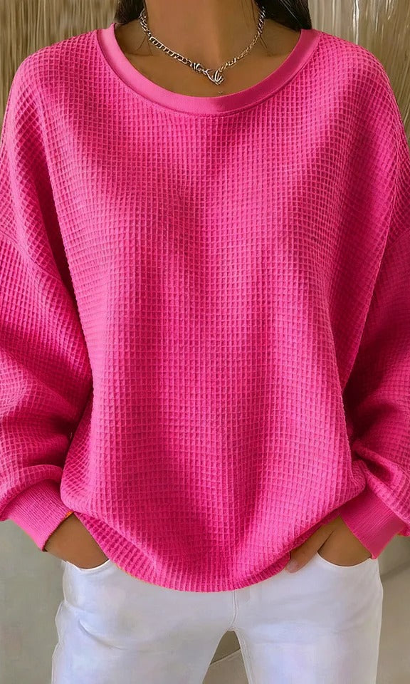 A model smiling while wearing the Odette knit sweater in fuchsia, showcasing comfort and confidence.