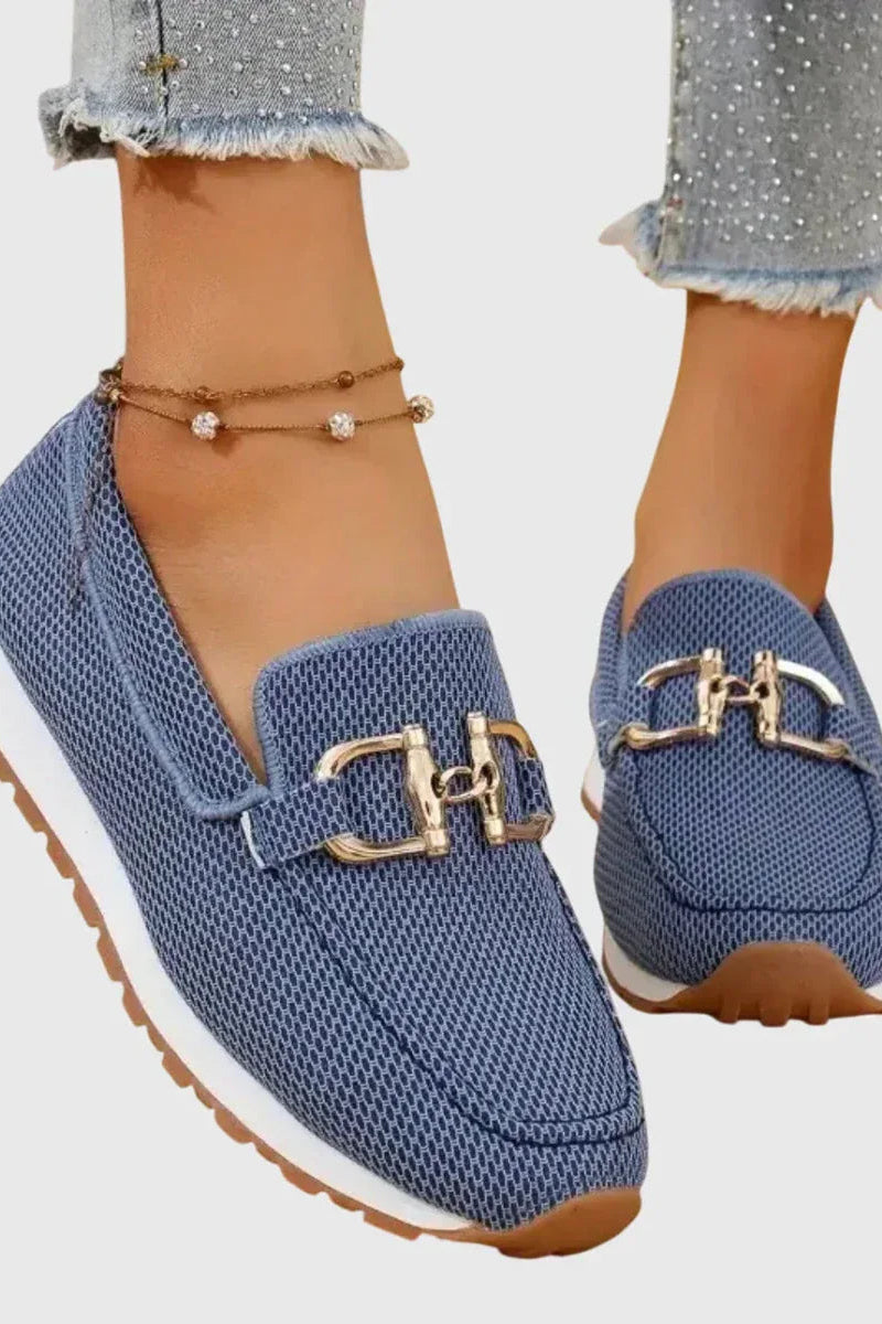 Close-up of the gold clasp detail on blue orthopedic pants, emphasizing the sporty elegance.