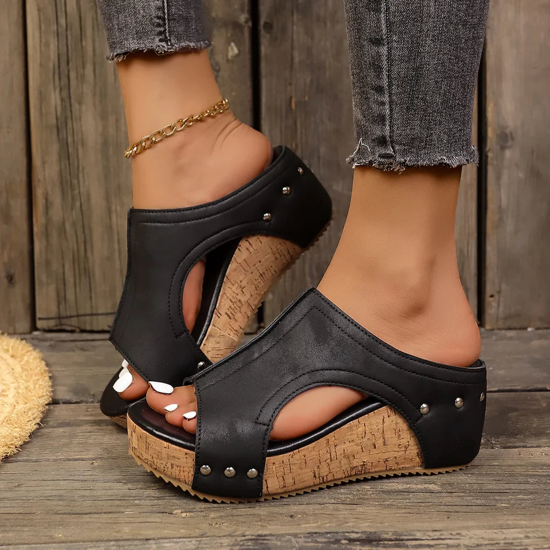 Front view of Solange studded wedge sandals in black, showcasing the metallic detailing and heel height.