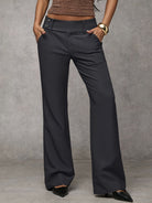 Detail shot of the waistband and top stitching on brown high-waisted trousers, showing craftsmanship.