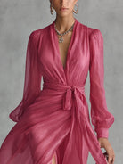 A woman wearing the flowing pearlescent maxi dress, walking outdoors in a serene garden party setting.