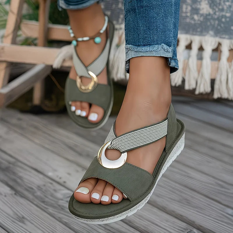 Close-up of the brushed gold-tone centre ring on the Artemis sandals where the straps meet.