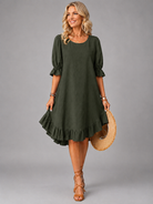 Side profile of a woman in a green Zenia dress, highlighting the soft drape and midi length.
