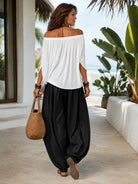 Side profile of a model wearing the flowing black trousers, showcasing their relaxed drape.