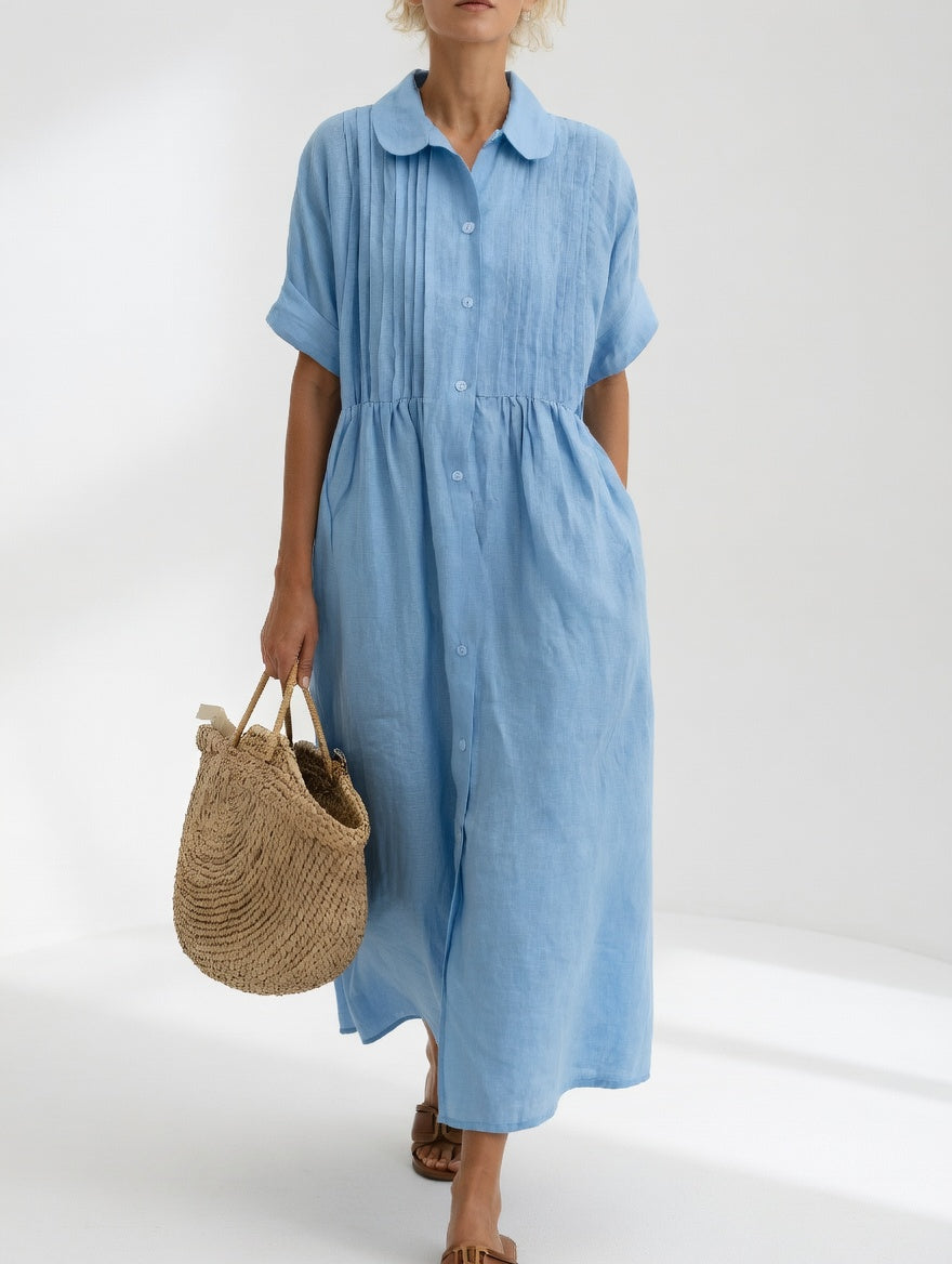 Side profile of a woman wearing a light blue cotton dress, highlighting the flowing silhouette and short sleeves.