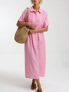 Lifestyle shot of a woman strolling outdoors in a yellow maxi shirt dress, emphasizing comfort and natural style.