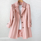 Side profile of a woman wearing the Adeline trench coat in khaki, showcasing its flowing silhouette and length.