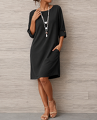 Side profile of a woman showcasing the flowing silhouette of the black midi dress, walking confidently.