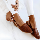 Pair of dark brown handcrafted moccasins from a top-down view, showcasing the woven detail and soft texture.