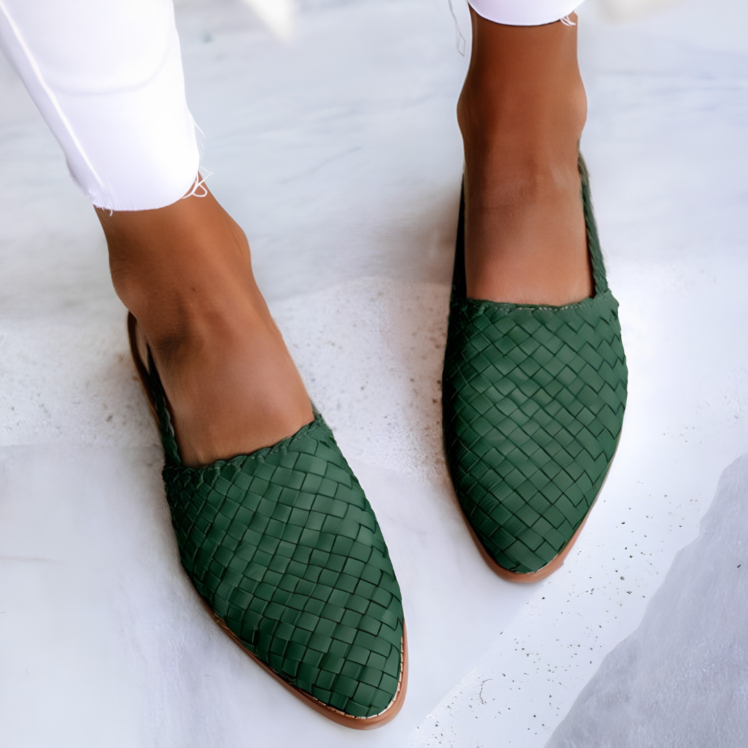 Side profile of a green handcrafted moccasin on a light background, highlighting the flexible sole and artisanal stitching.