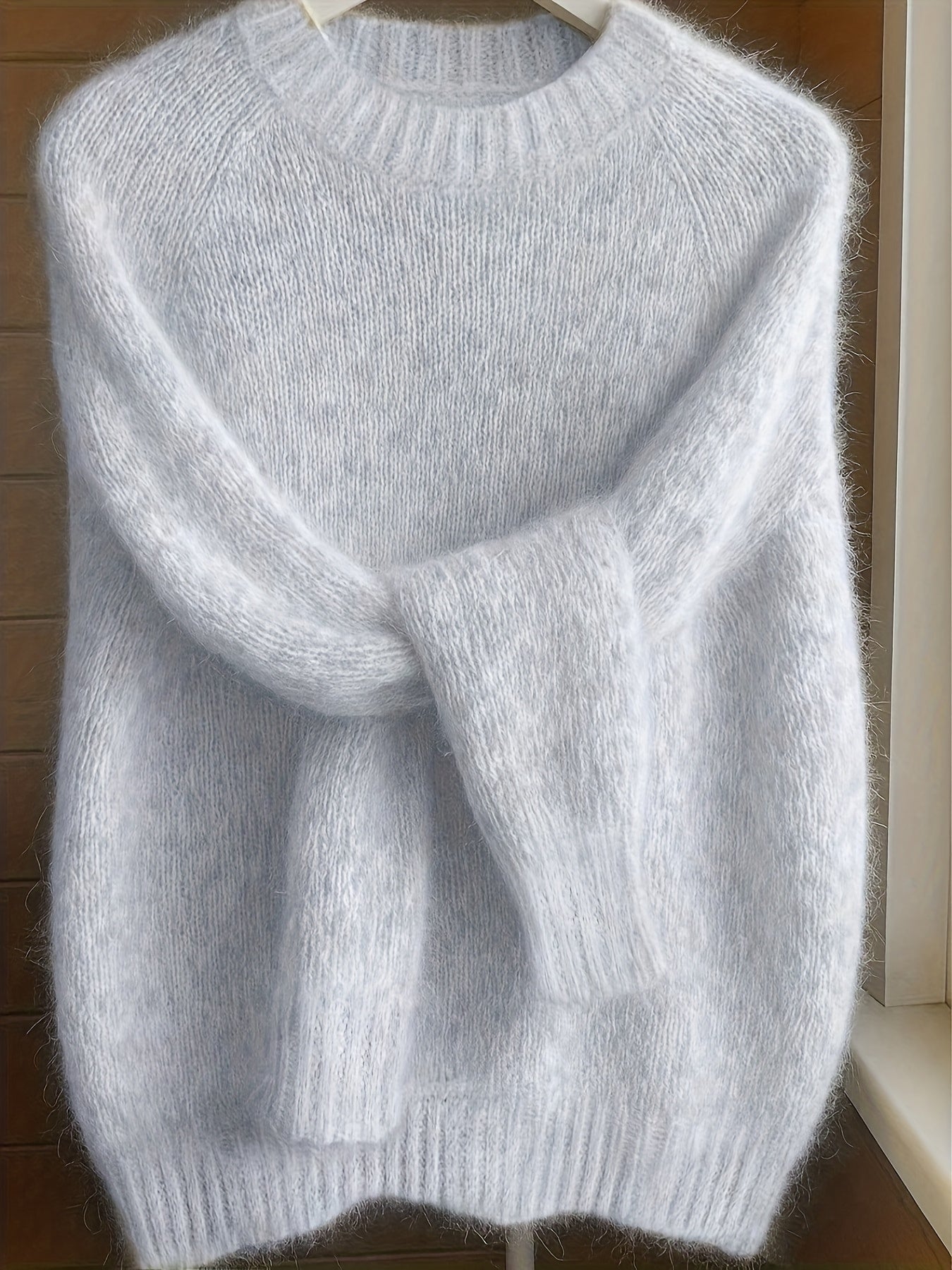 Side profile of a woman in the light grey Elara cashmere-blend sweater, highlighting the elegant silhouette and sleeve length.