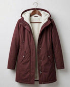A woman wearing the Elara waterproof parka in a natural outdoor setting, protected from light rain.