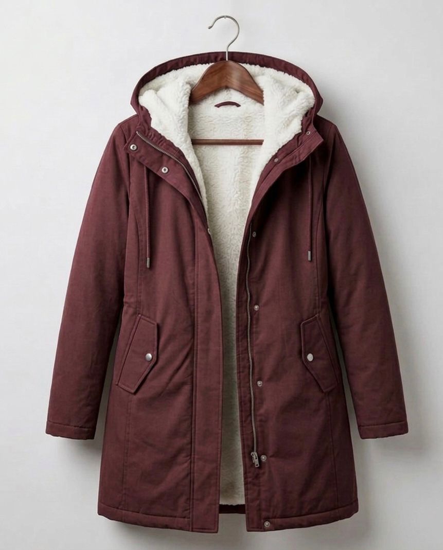 A woman wearing the Elara waterproof parka in a natural outdoor setting, protected from light rain.